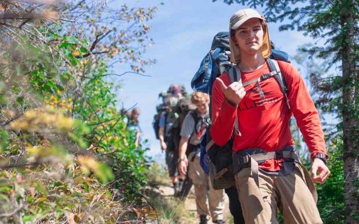 a group of gap year students hike along a trail surrounded by greenery on an outward bound expedition 
